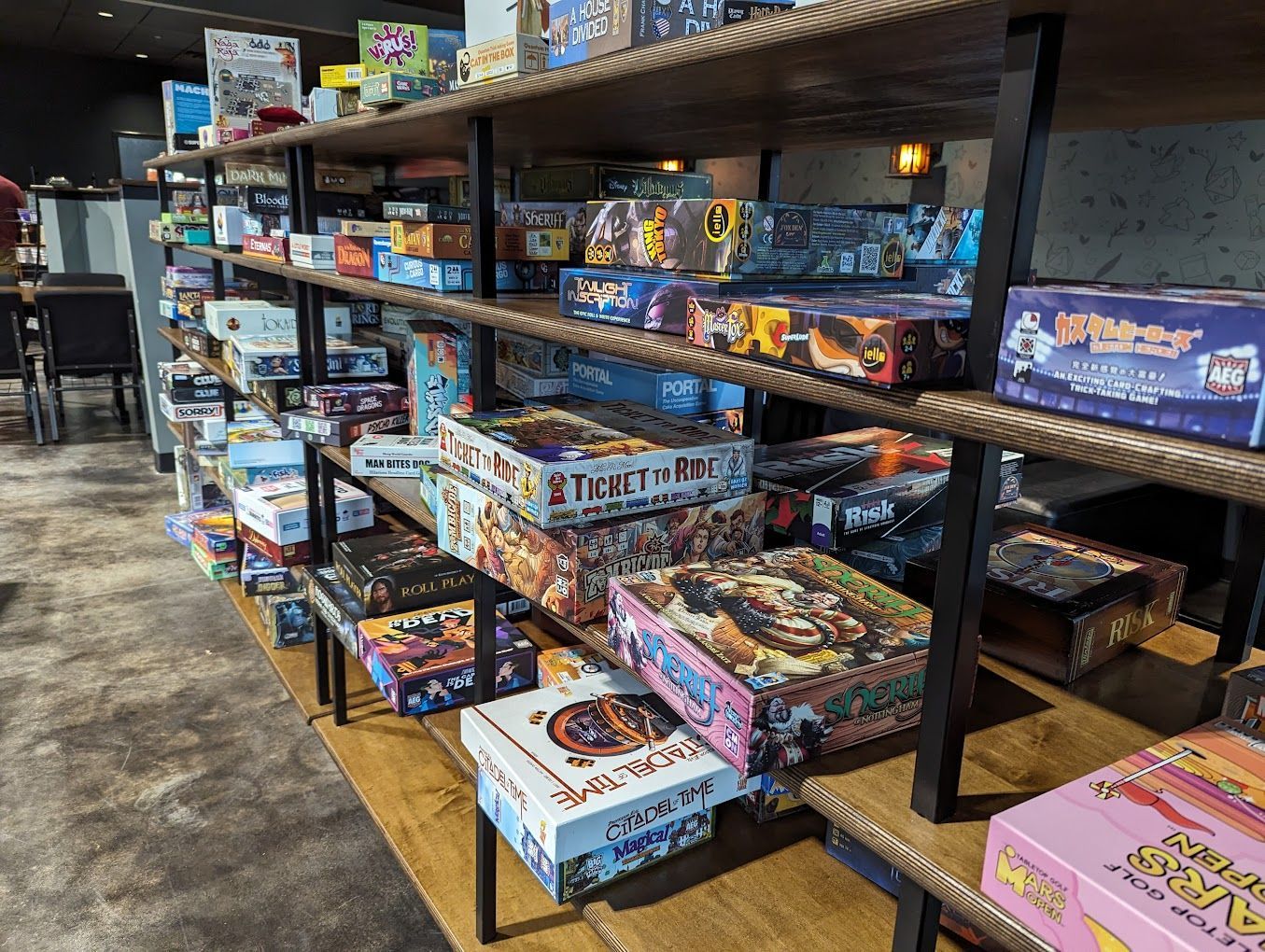 Shelves filled with various board game boxes in a brightly lit room.