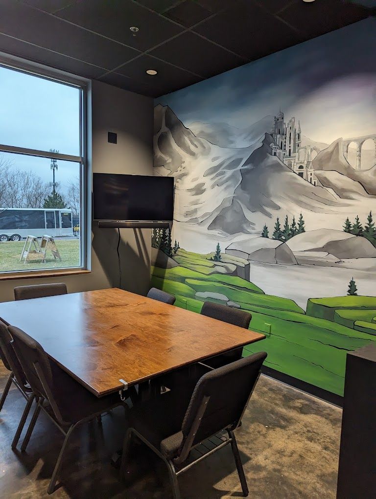 Meeting room with table, chairs, TV, window, and mountain mural.