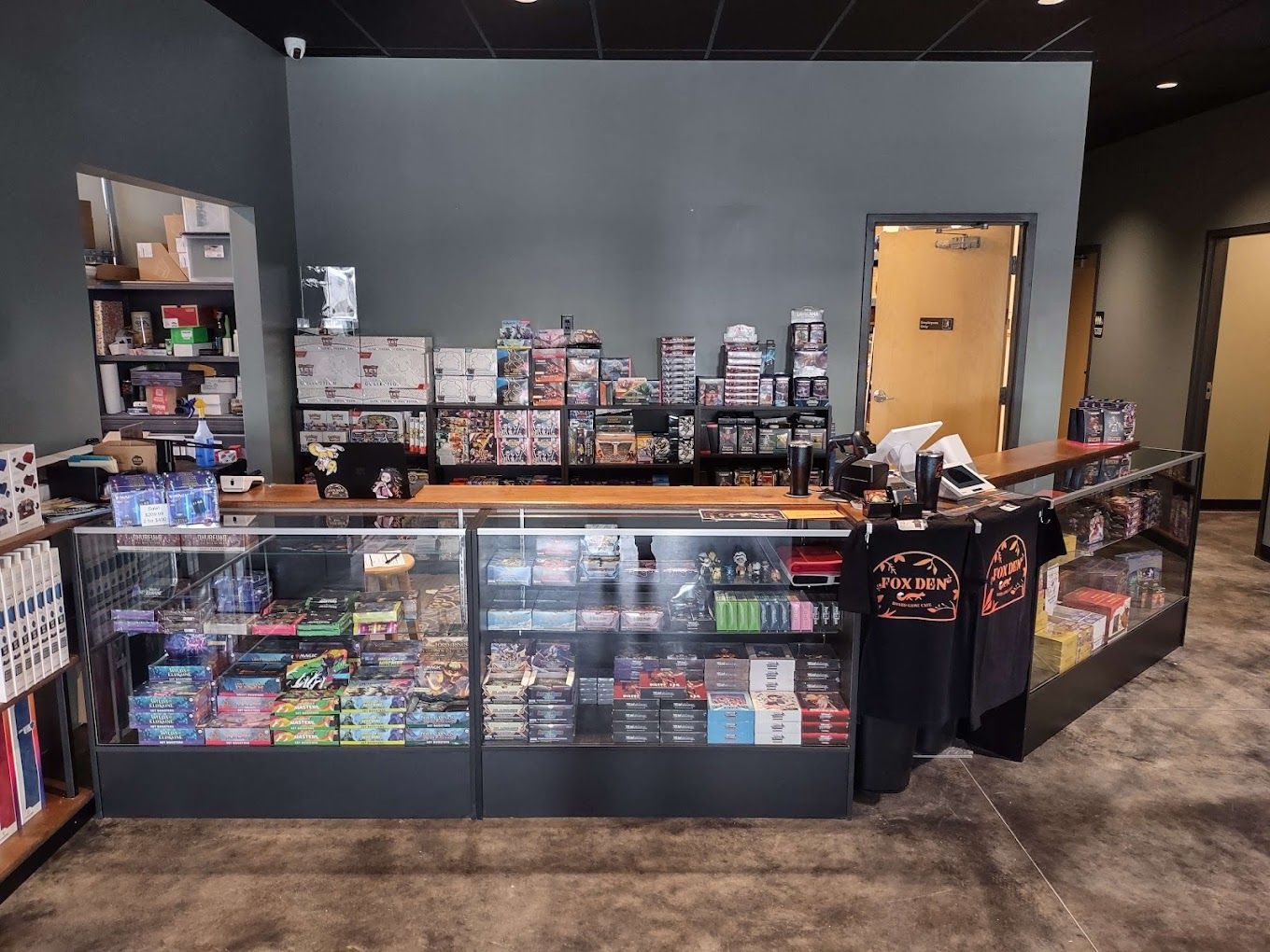 Inside a game store, a checkout counter is filled with merchandise.