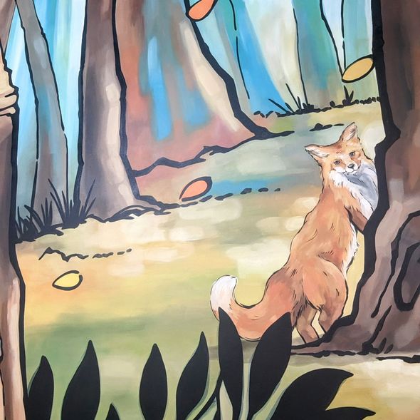 Fox peeks from behind a tree in a colorful forest with falling leaves.
