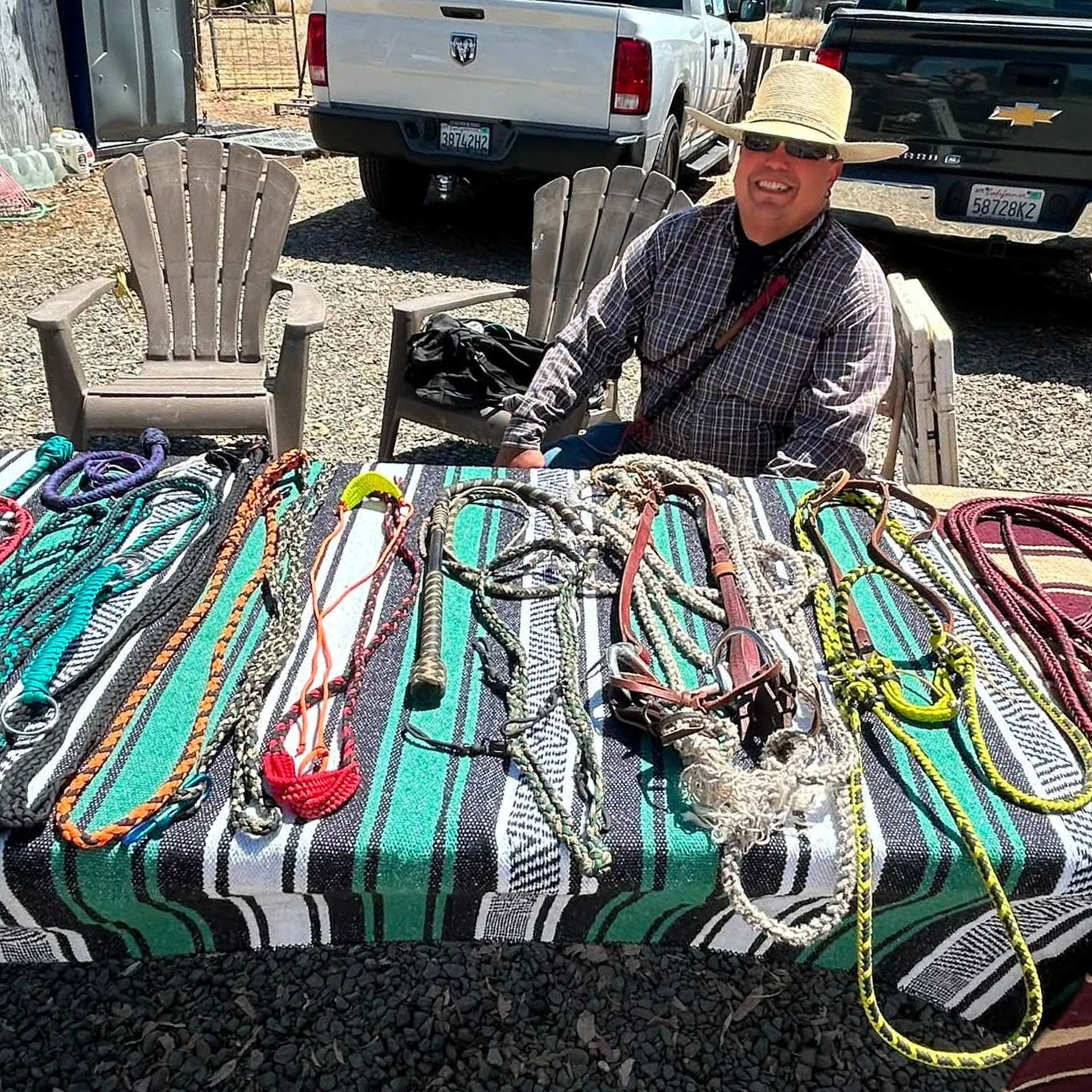 Vendor sitting behind a table of colorful woven belts and ropes at an outdoor market