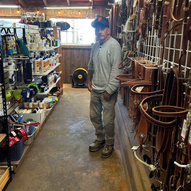 Person standing in a narrow hardware shop aisle beside shelves of tools and hanging metal racks