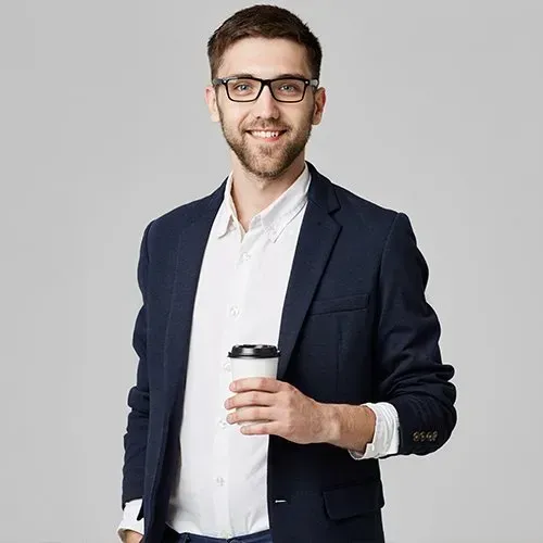 Man in glasses and suit jacket, holding coffee cup, smiling.
