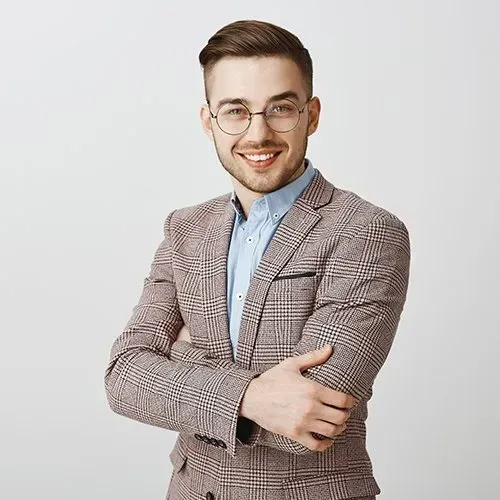 Man in glasses and plaid blazer, arms crossed, smiling at the camera.