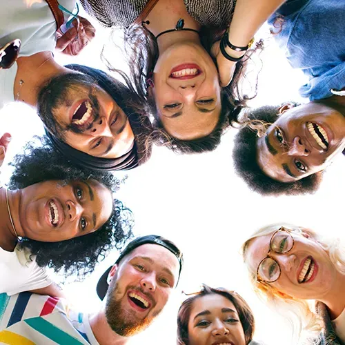 Group of diverse people smiling and looking down towards the camera.