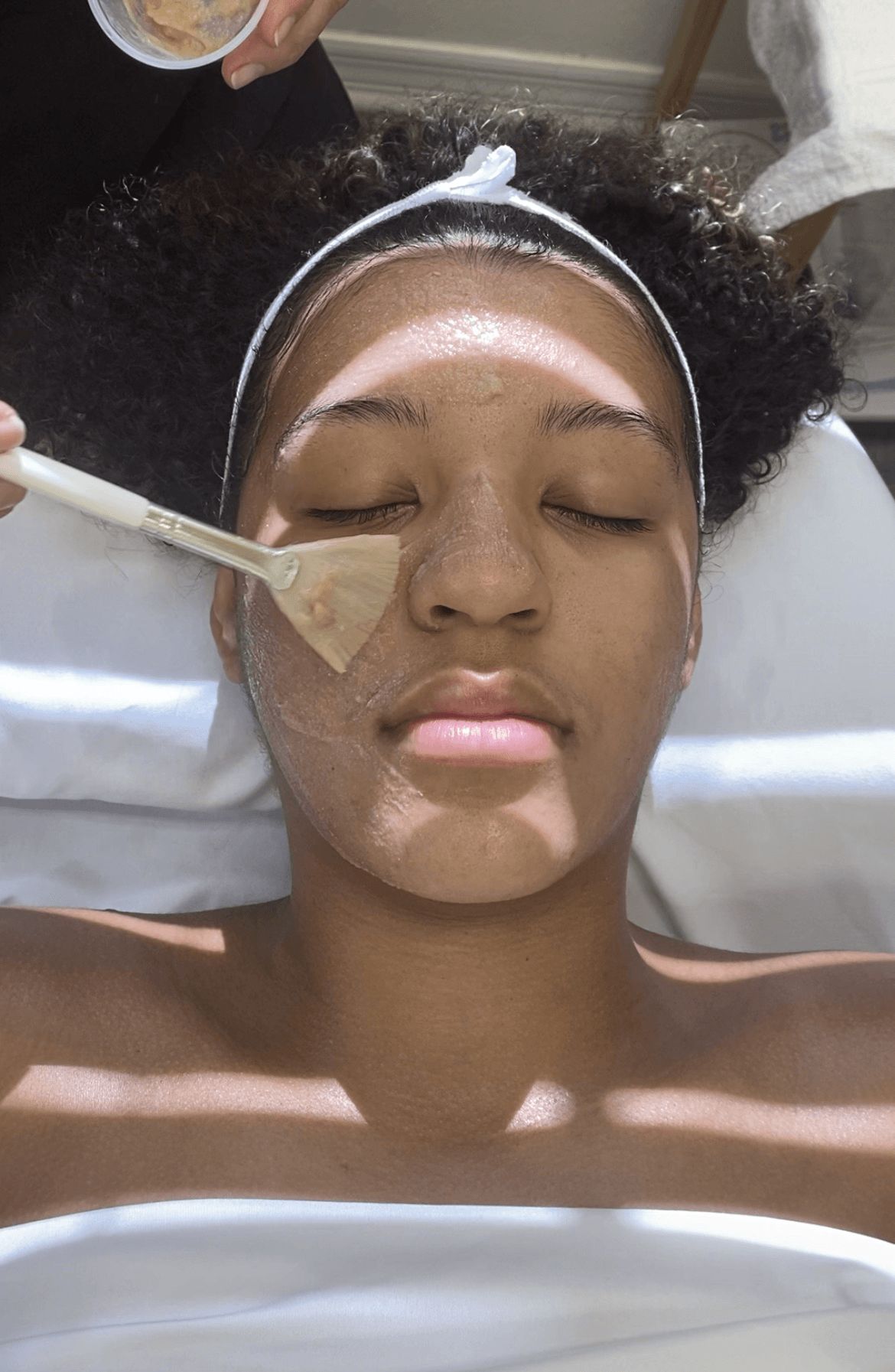 Enzyme treatment applied with fan brush to client's cheek area