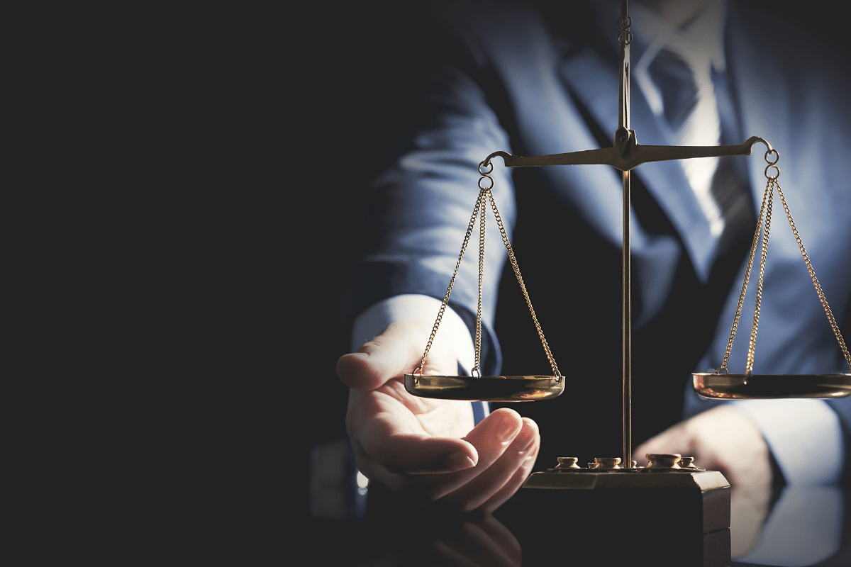 A man in a suit is holding a scale of justice in his hand.