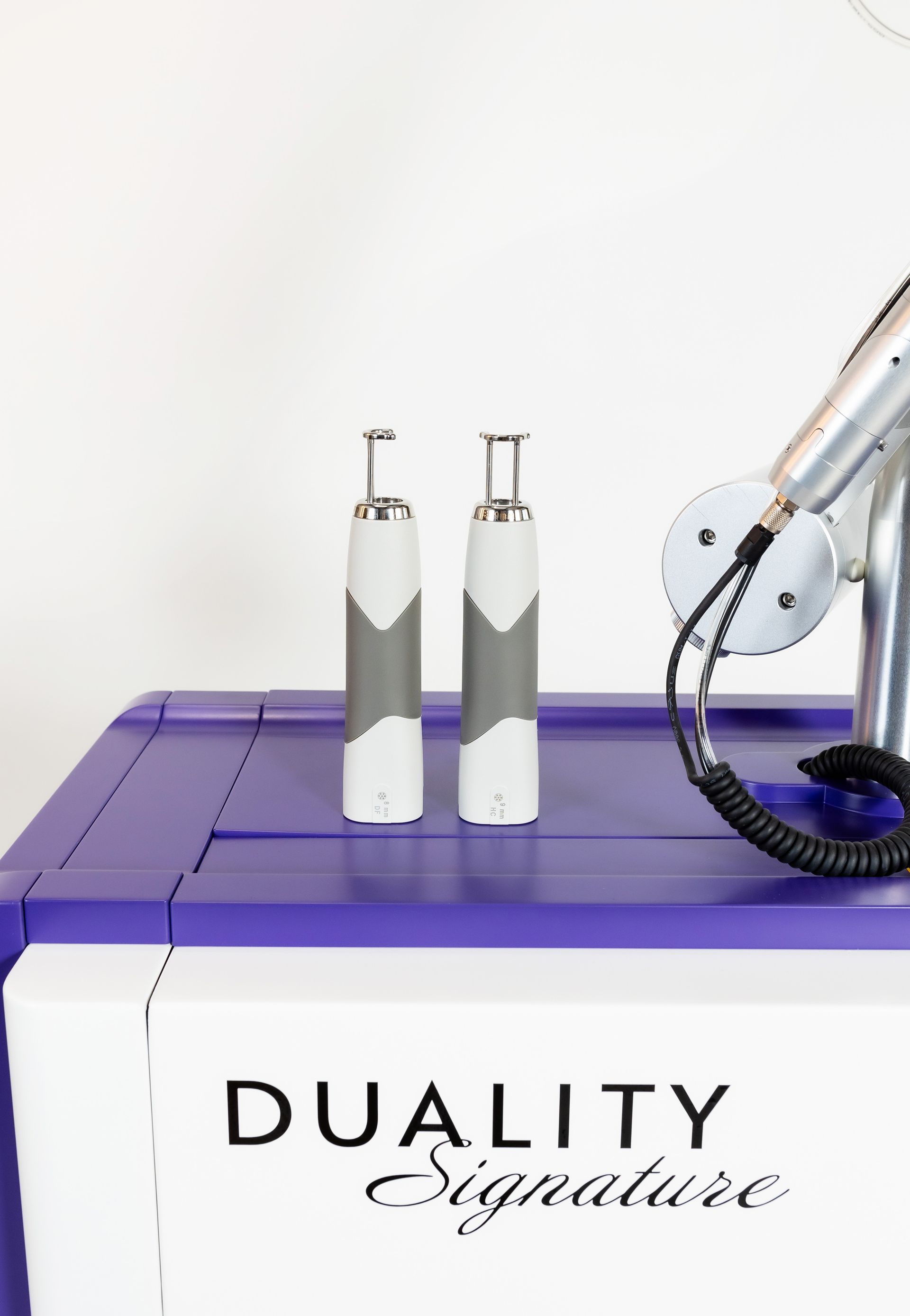 Two white and gray handheld medical devices sit on a purple and white machine.