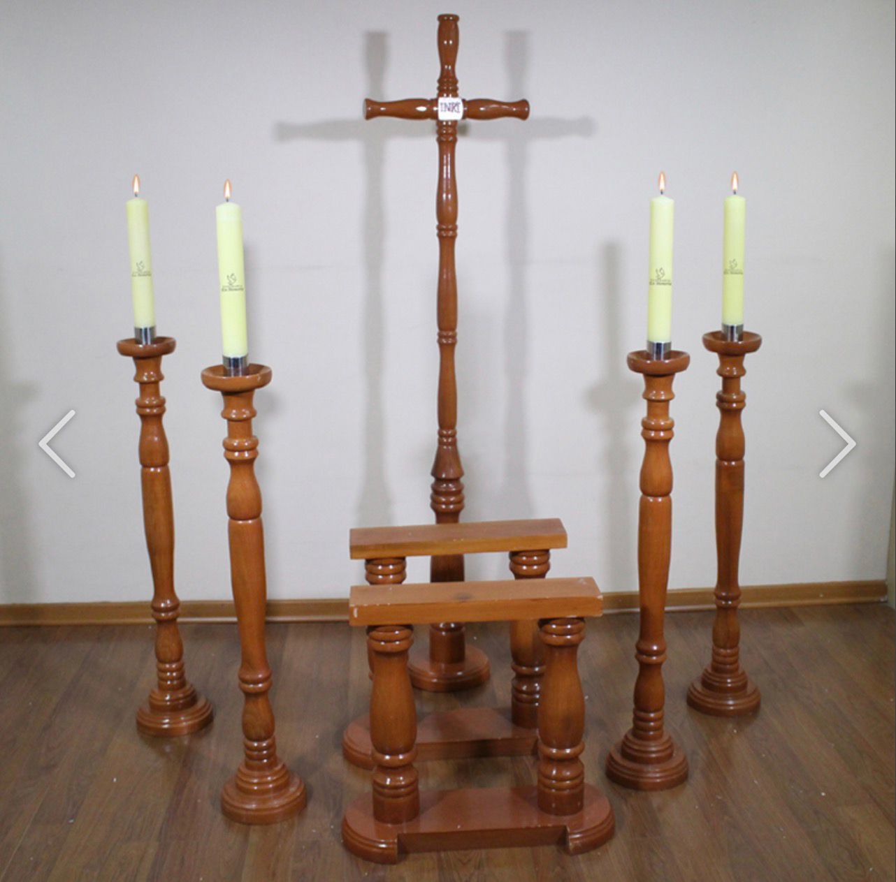 Conjunto de altar religioso de madera con cruz, velas y soporte sobre piso de madera.
