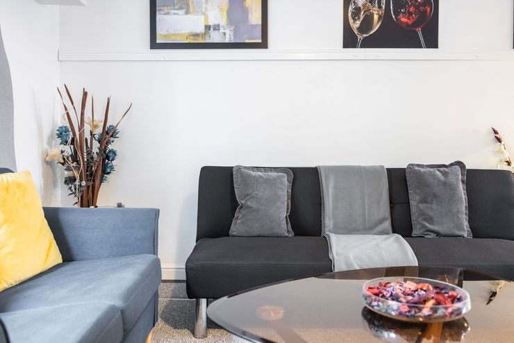 Modern living room with black and blue sofas, coffee table, and wall art