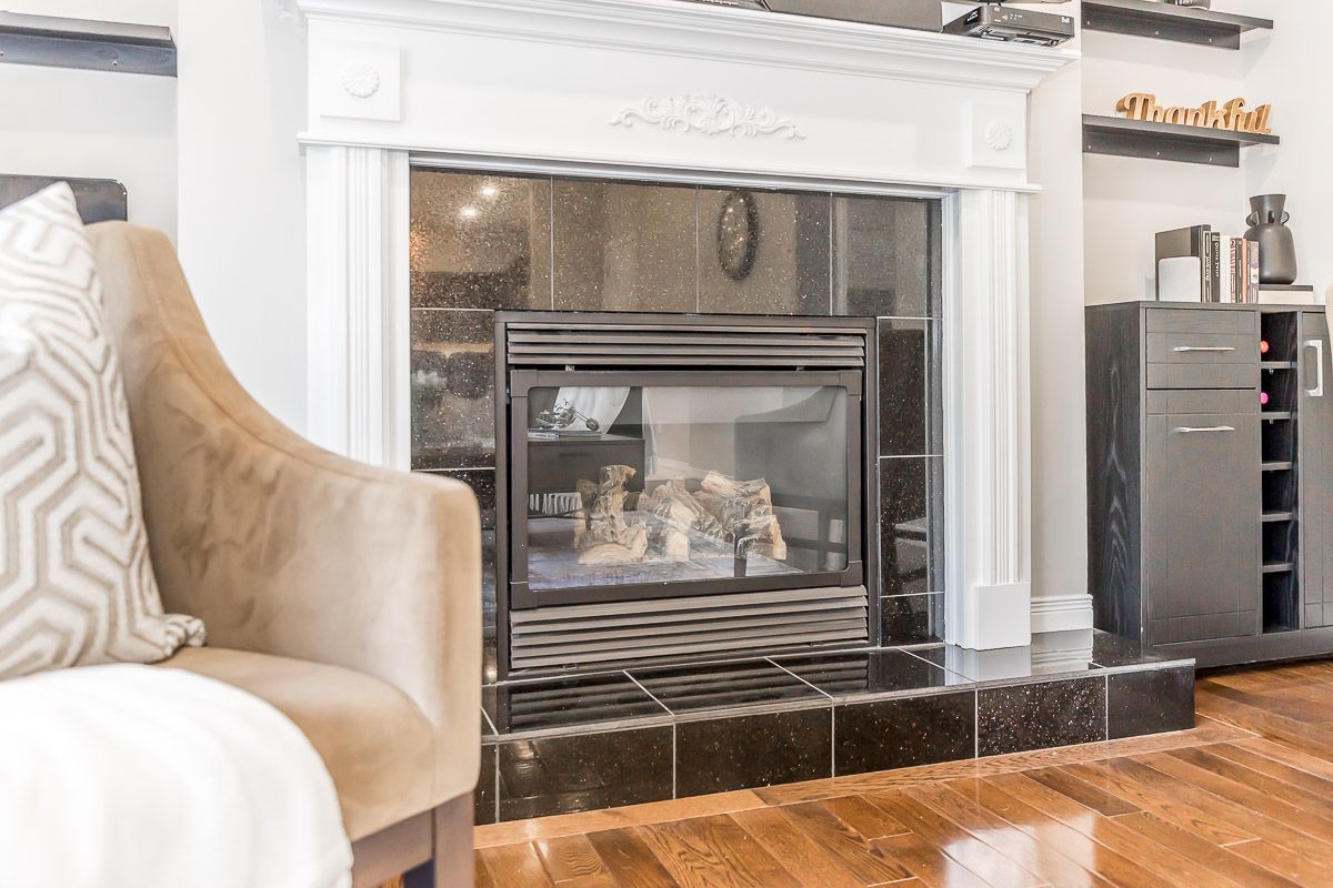 Fireplace with black surround, white mantel, and tan armchair.