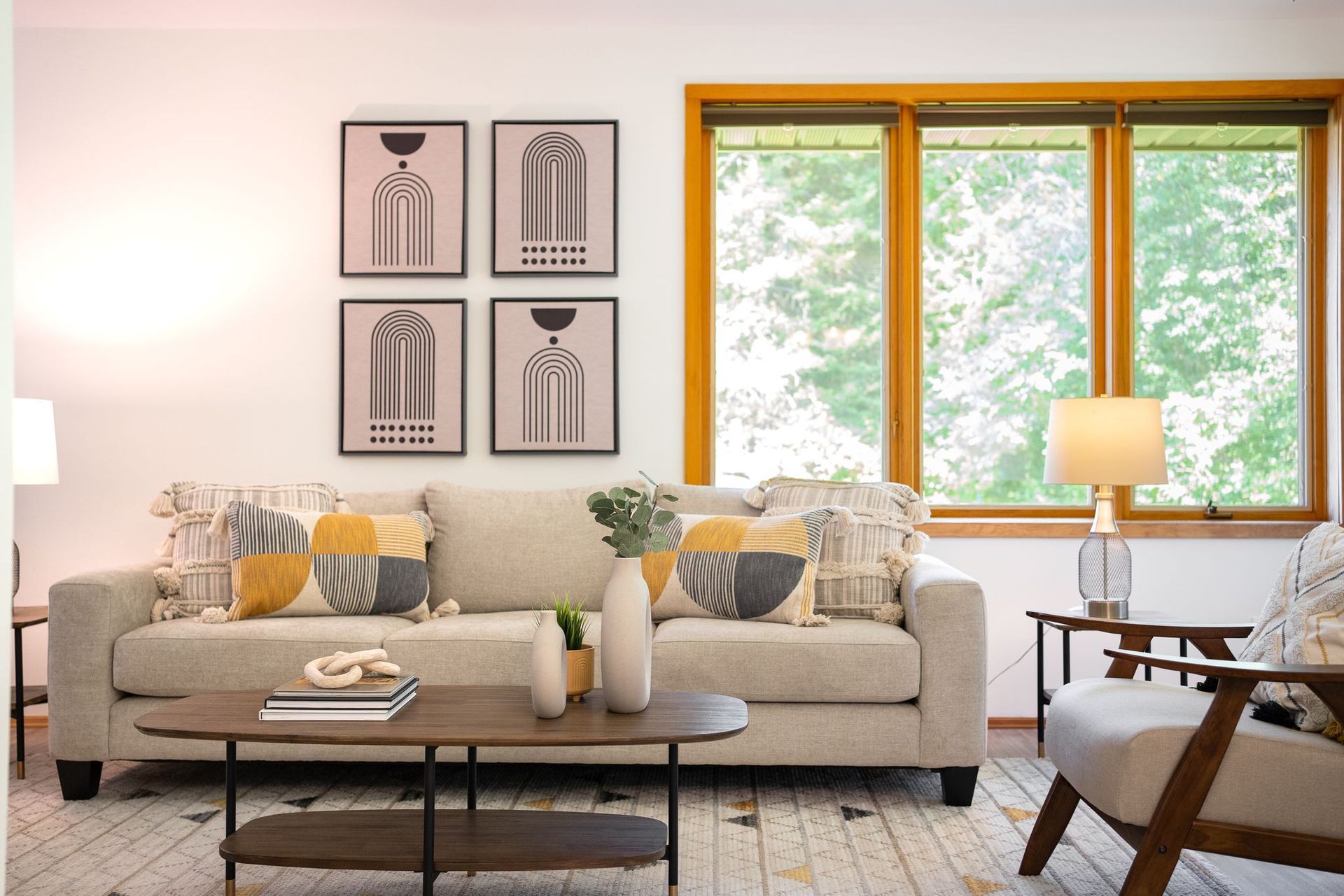 Living room with a beige sofa, geometric art, and a large window.