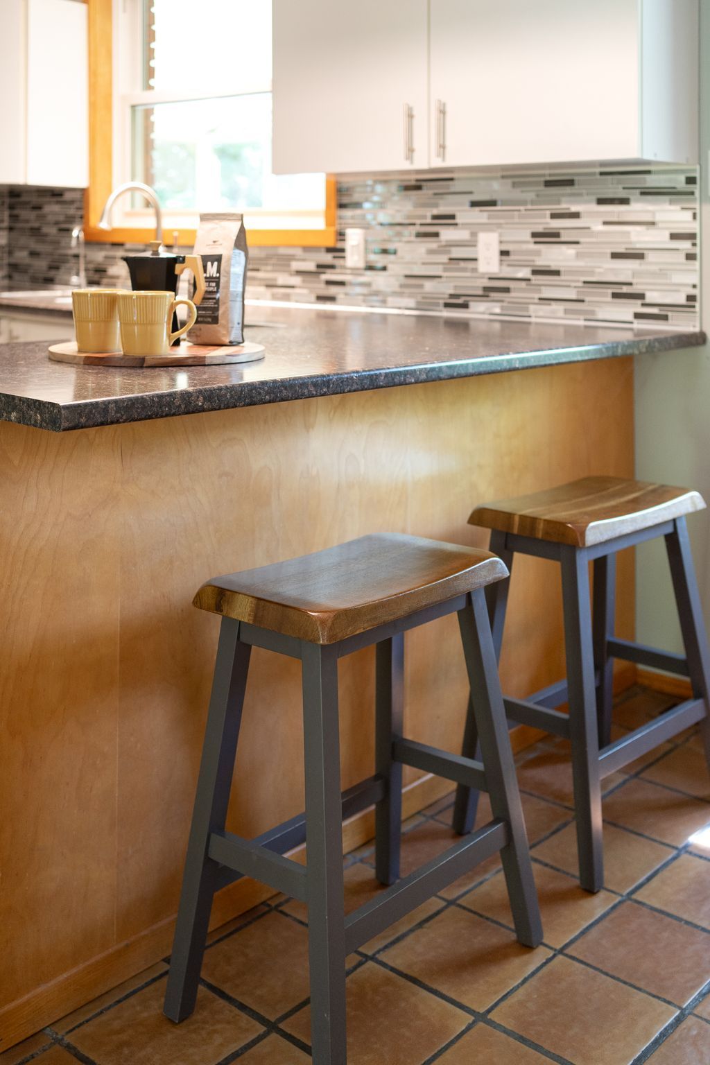 Two wooden bar stools at a kitchen counter with a textured, golden-toned wall.