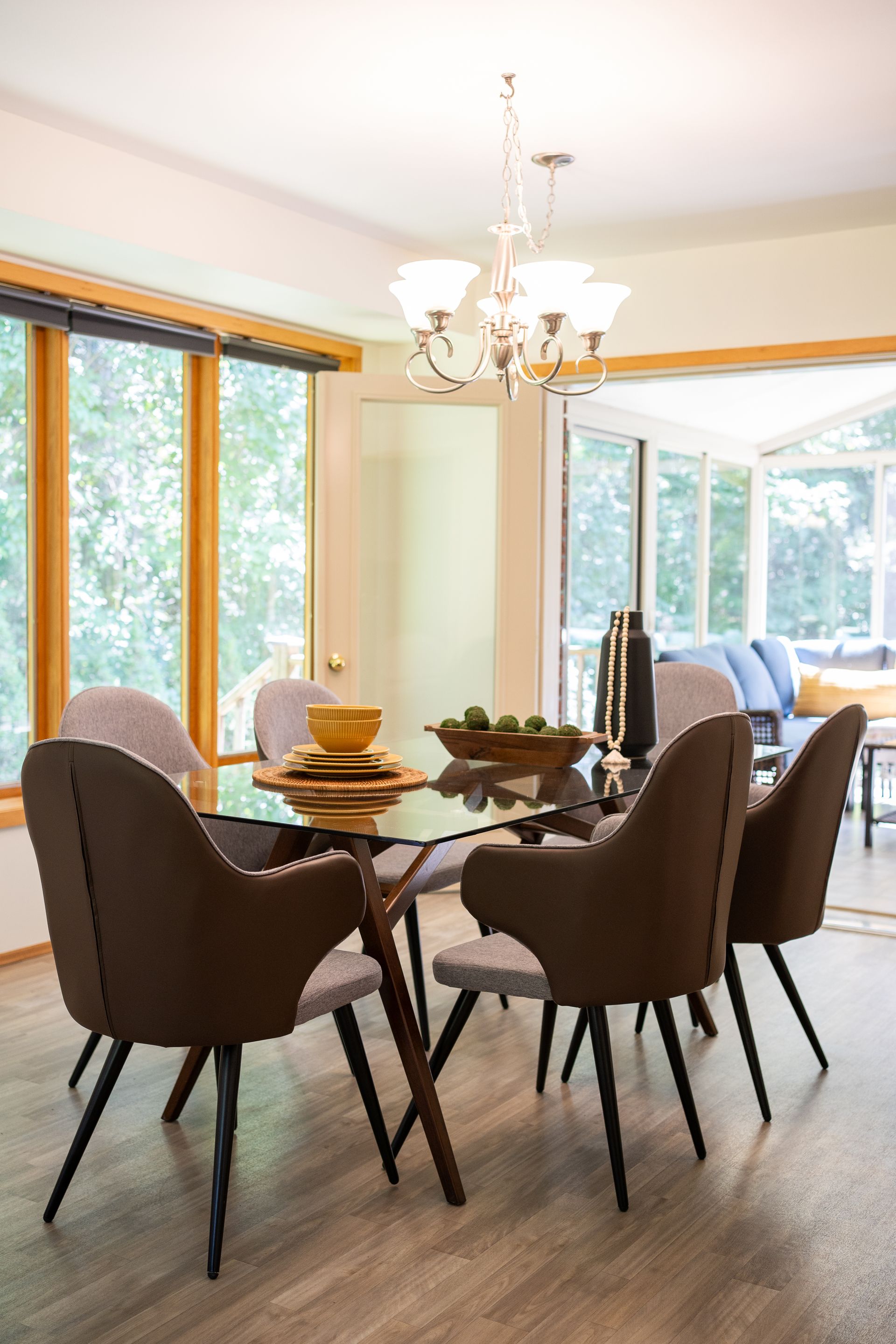 Dining room with glass table, brown chairs, and chandelier.