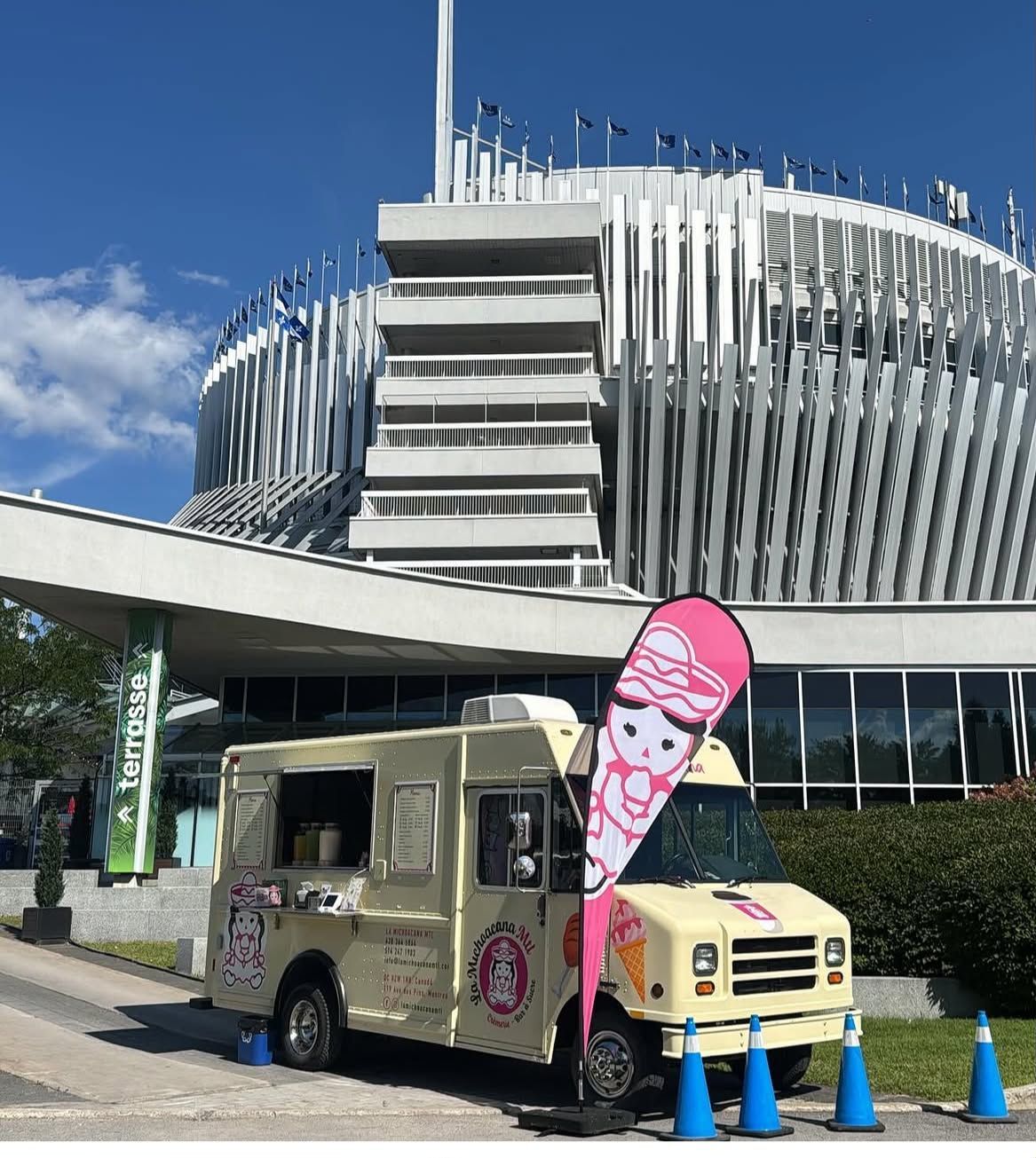 Une personne tenant une glace rouge partiellement mangée devant une foire avec des stands de nourriture et des gens.