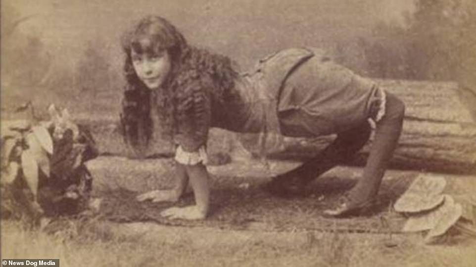 Girl with contorted legs and arms posed on hands and knees near logs and leaves.