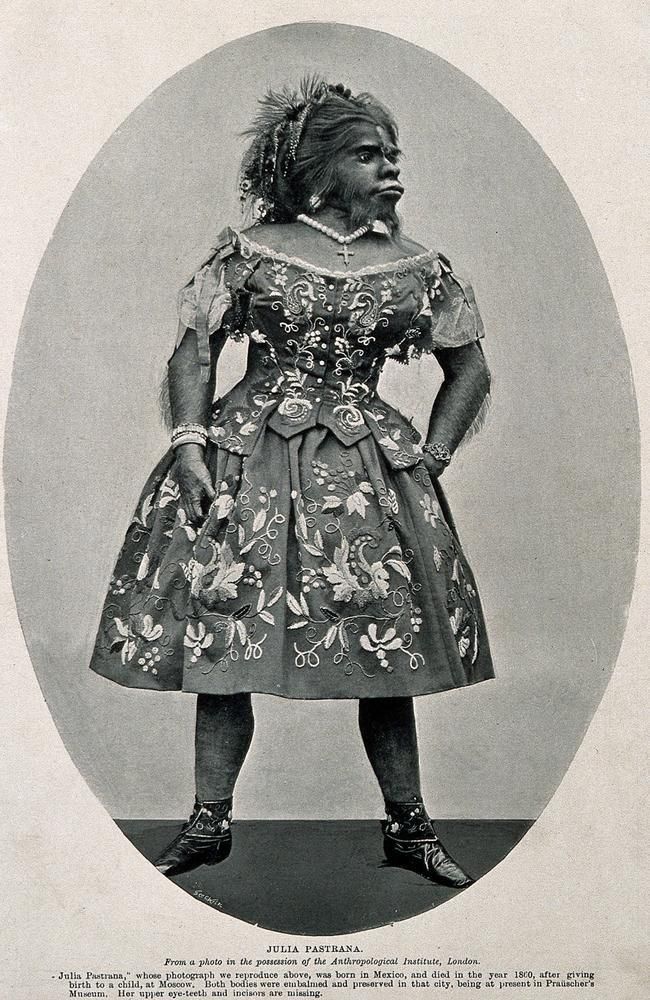 Oval portrait of a person in a decorated dress. The person has a dark complexion, and is standing with hands on hips.