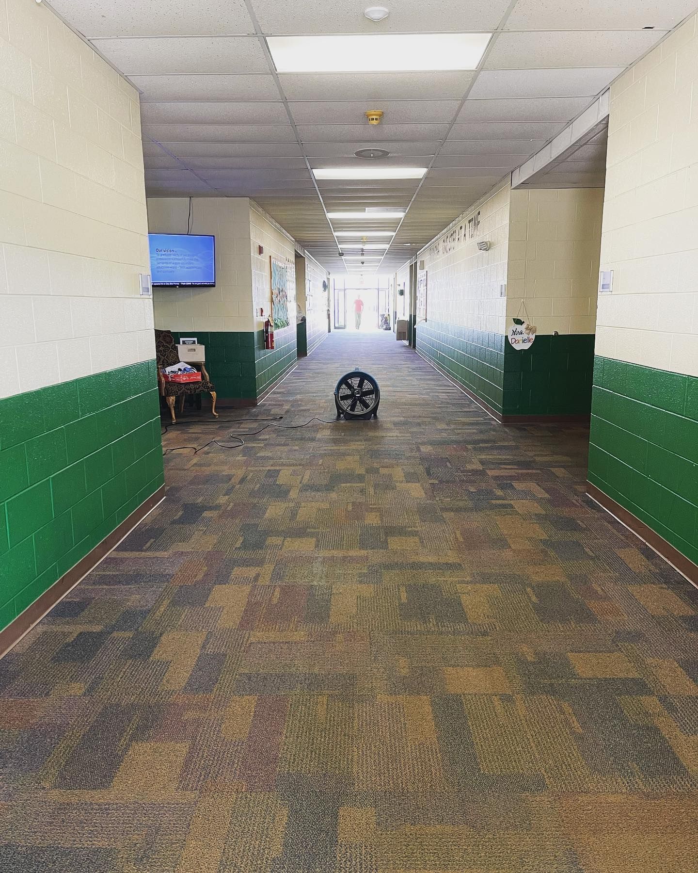 A long hallway with green walls and a wheel on the floor.