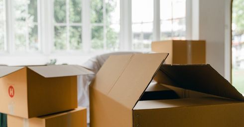 A bunch of cardboard boxes are stacked on top of each other in a living room.