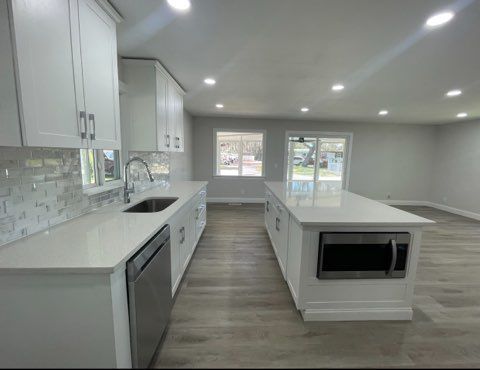 Bright modern kitchen with white cabinets, large island, and gray wood flooring