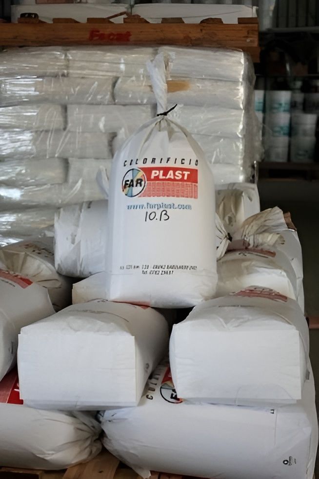 Pile di sacchi di plastica bianca in un'area di stoccaggio, uno dei quali con l'etichetta 