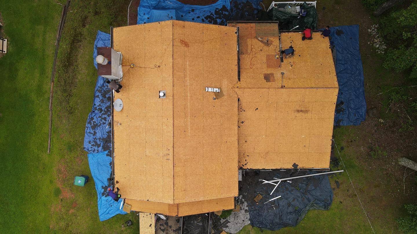 An aerial view of a house under construction with workers on the roof.