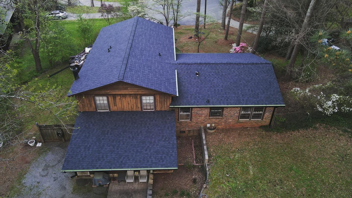 An aerial view of a house with a blue roof surrounded by trees.