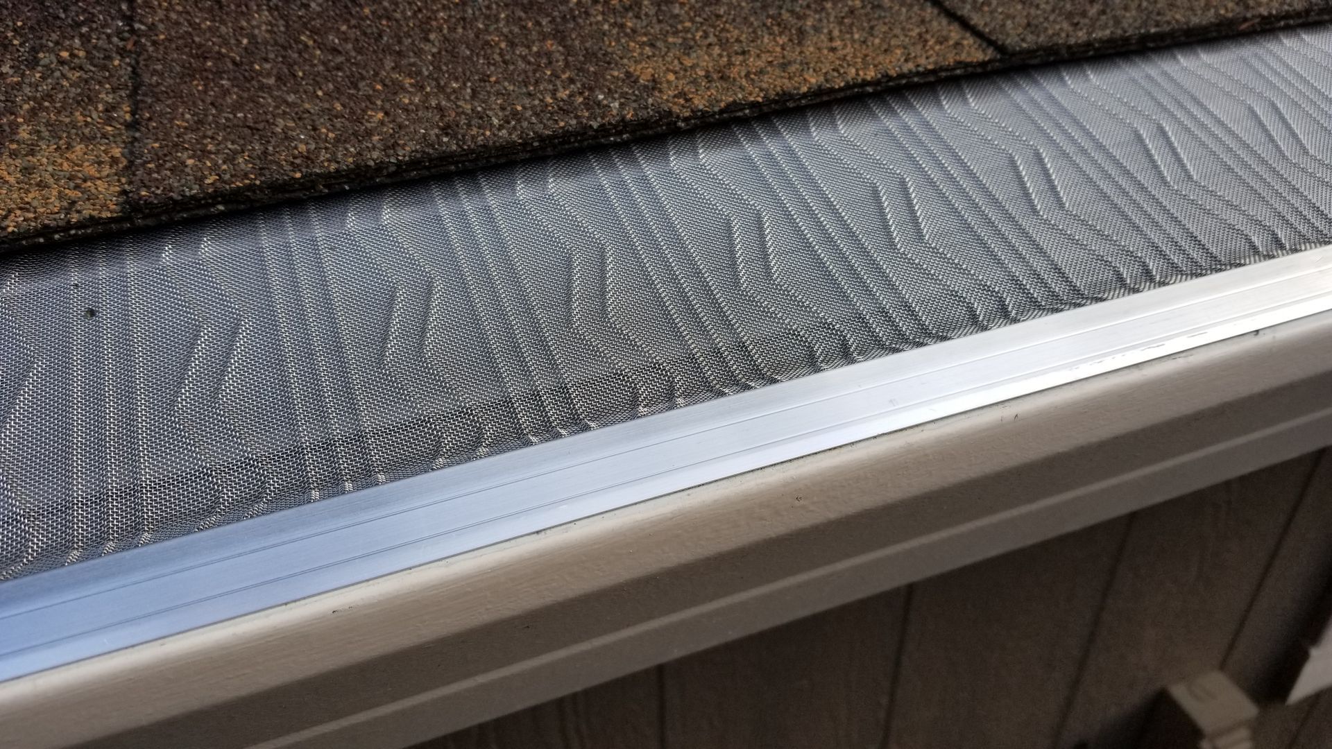 A close up of a gutter on a roof with water on it.