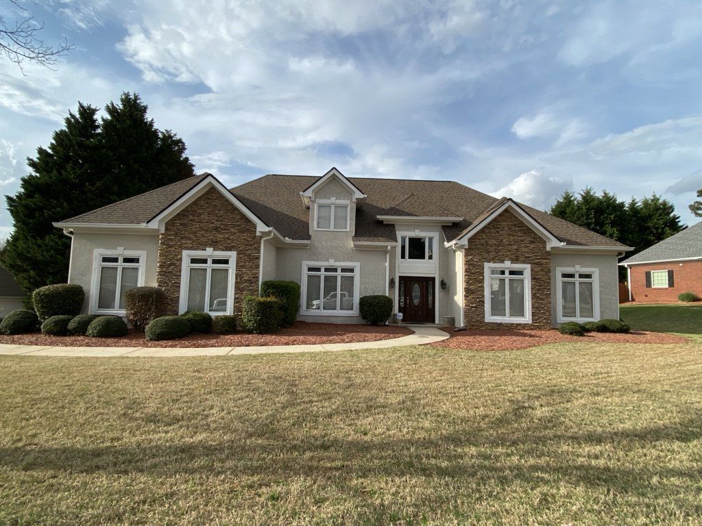 A large white house with a brown roof and a lot of windows