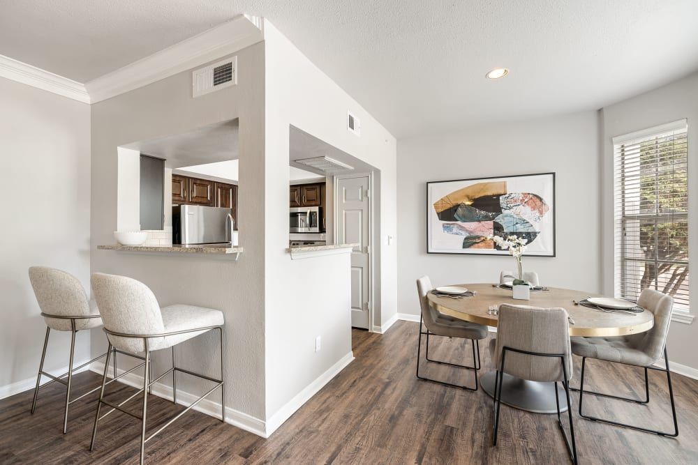 Apartment dining room with a table and chairs and the kitchen in the background at Marquis at Stonegate offers apartments with work-from-home space in Fort Worth, TX.