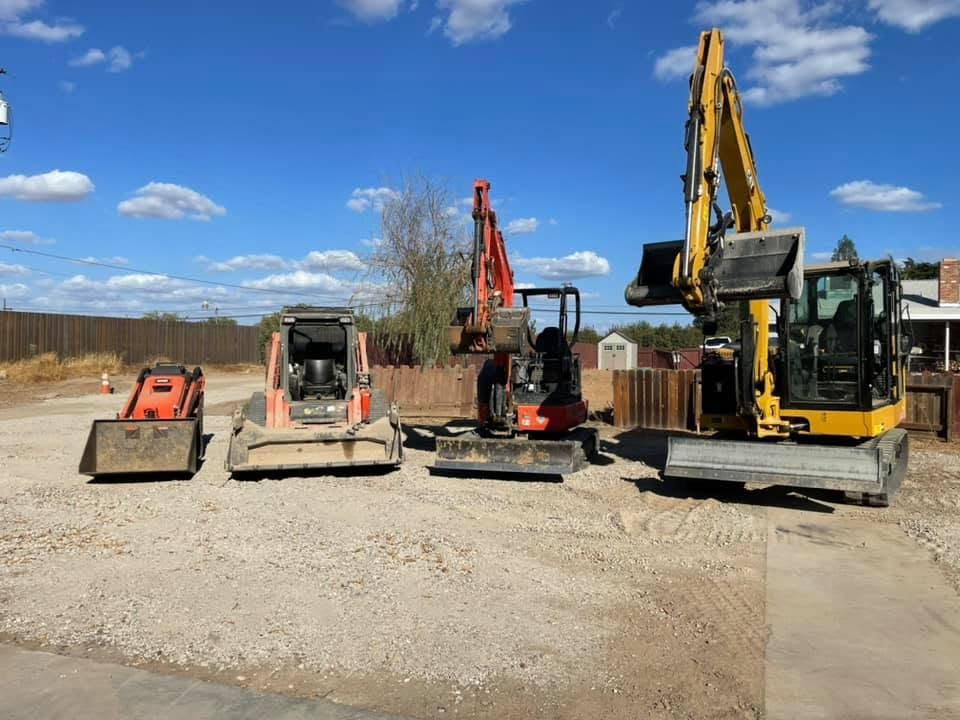 Construction equipment parked on a gravel lot under a blue sky