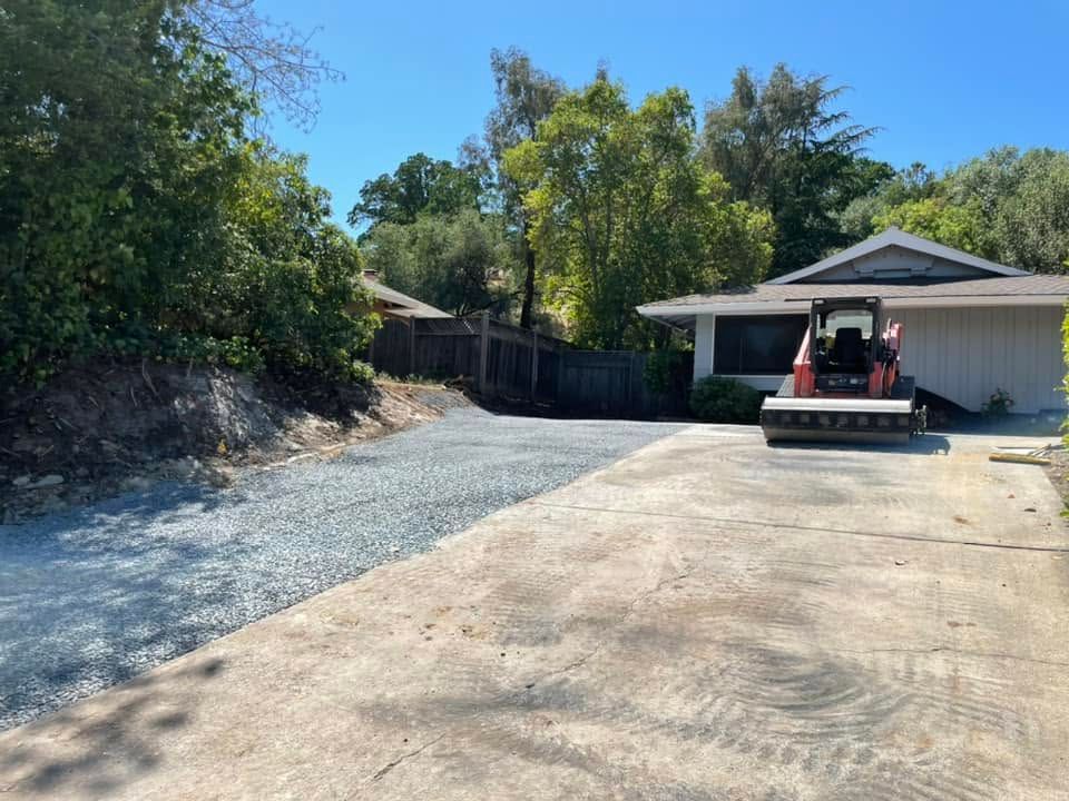 Driveway beside a house with a red skid steer parked in front of the garage.