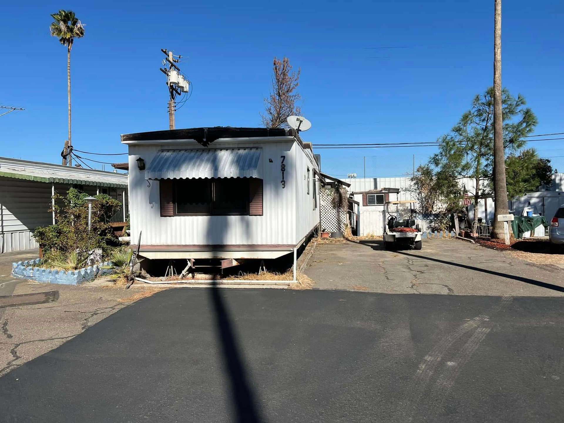 Mobile homes on a sunny lot with a large shadow in the foreground.