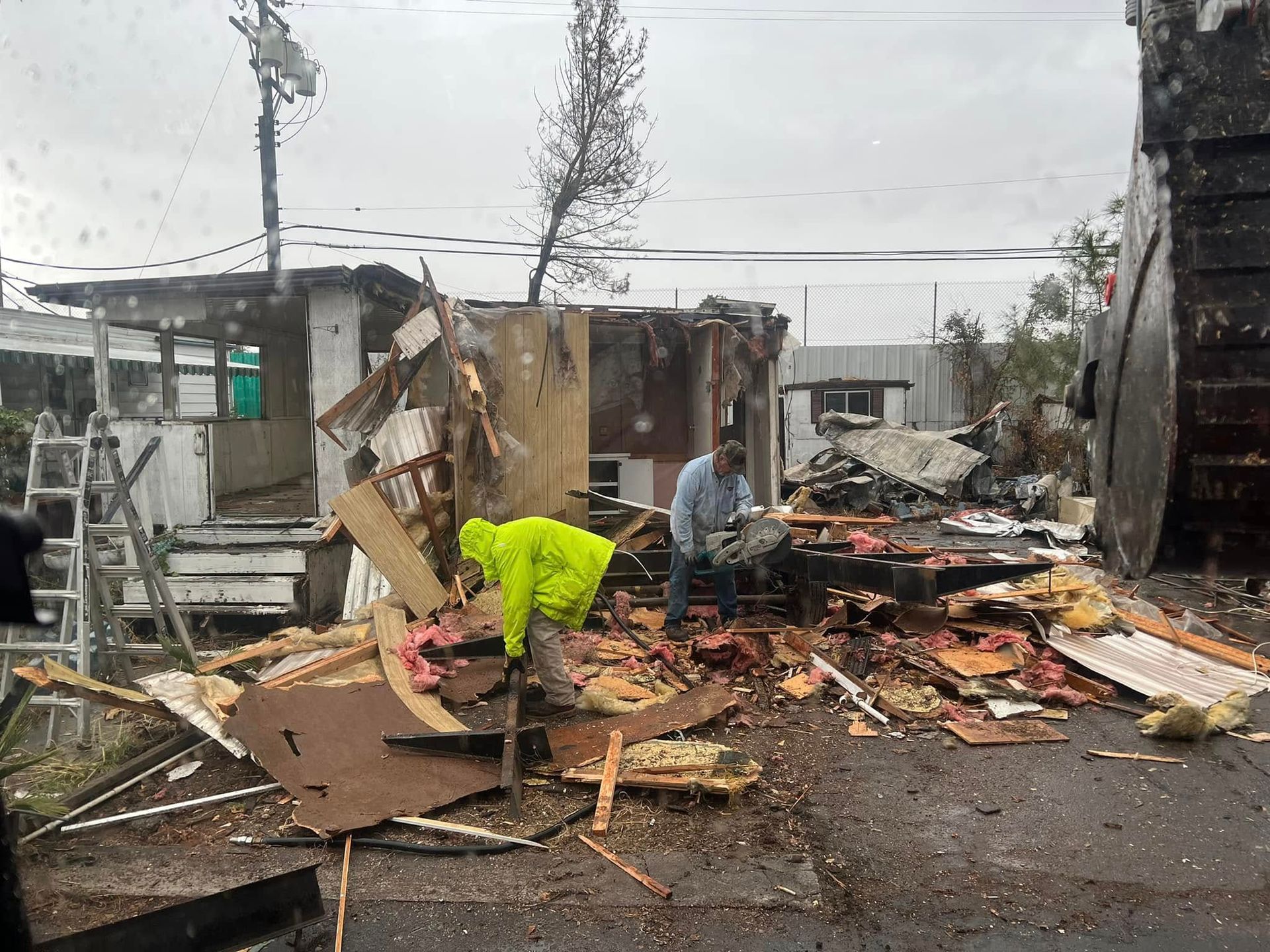 People cleaning storm debris outside a badly damaged building after a disaster