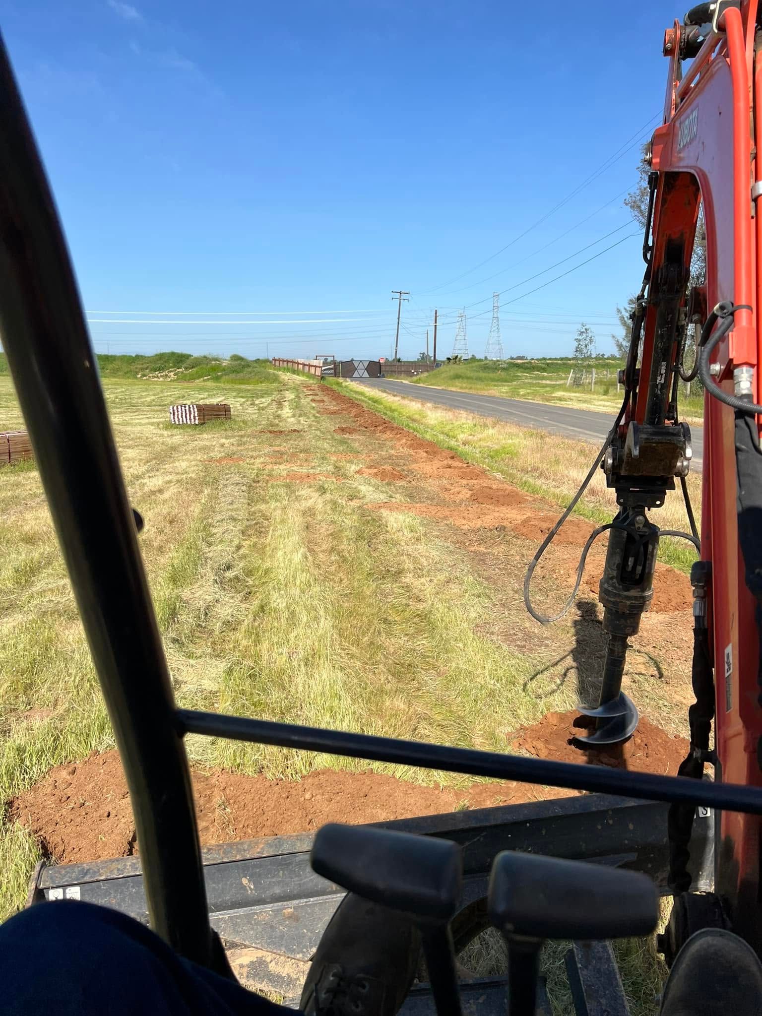 View from a vehicle over a grassy roadside beside a highway under a clear blue sky