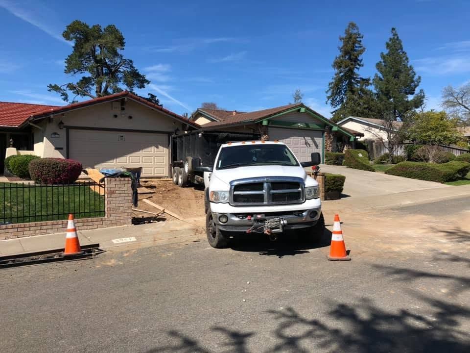 White pickup truck parked in a suburban driveway with orange cones and a garage in the background