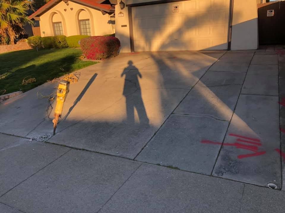 Driveway in front of a house at sunset, with a person’s shadow and chalk arrows on the concrete.