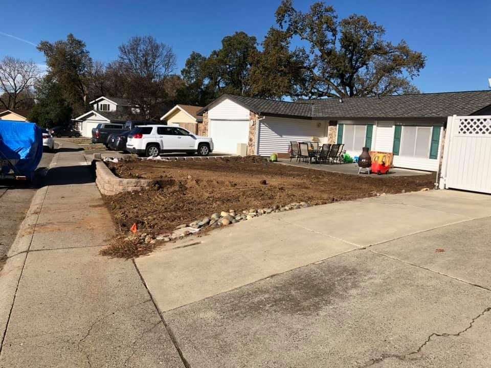 Residential driveway with a dirt front yard, parked pickup truck, and garage under clear blue sky