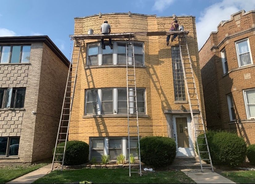Two men are working on the roof of a brick building.