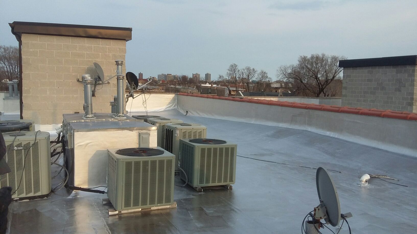 A rooftop with a lot of air conditioners and a satellite dish
