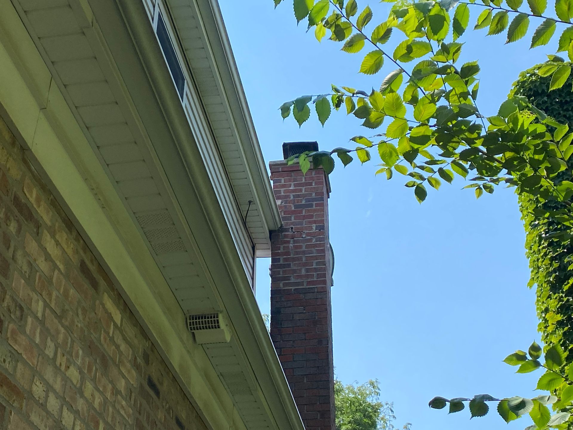 A brick chimney is on the side of a house.