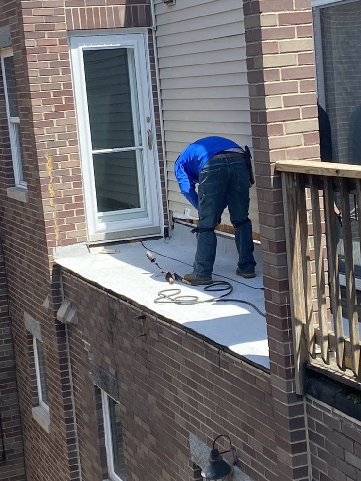 A man is working on the roof of a brick building.