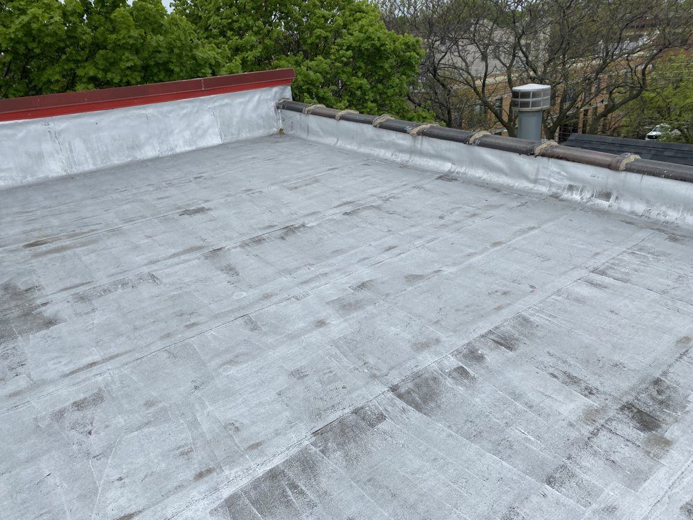A roof with a chimney on it and trees in the background.