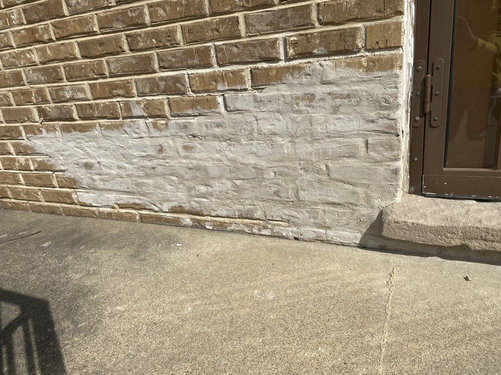 A brick wall with white paint on it and a door.