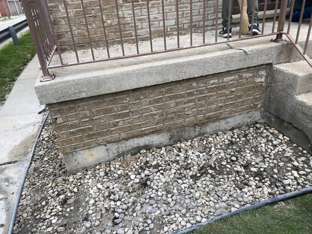 A person is standing next to a brick wall with a railing.