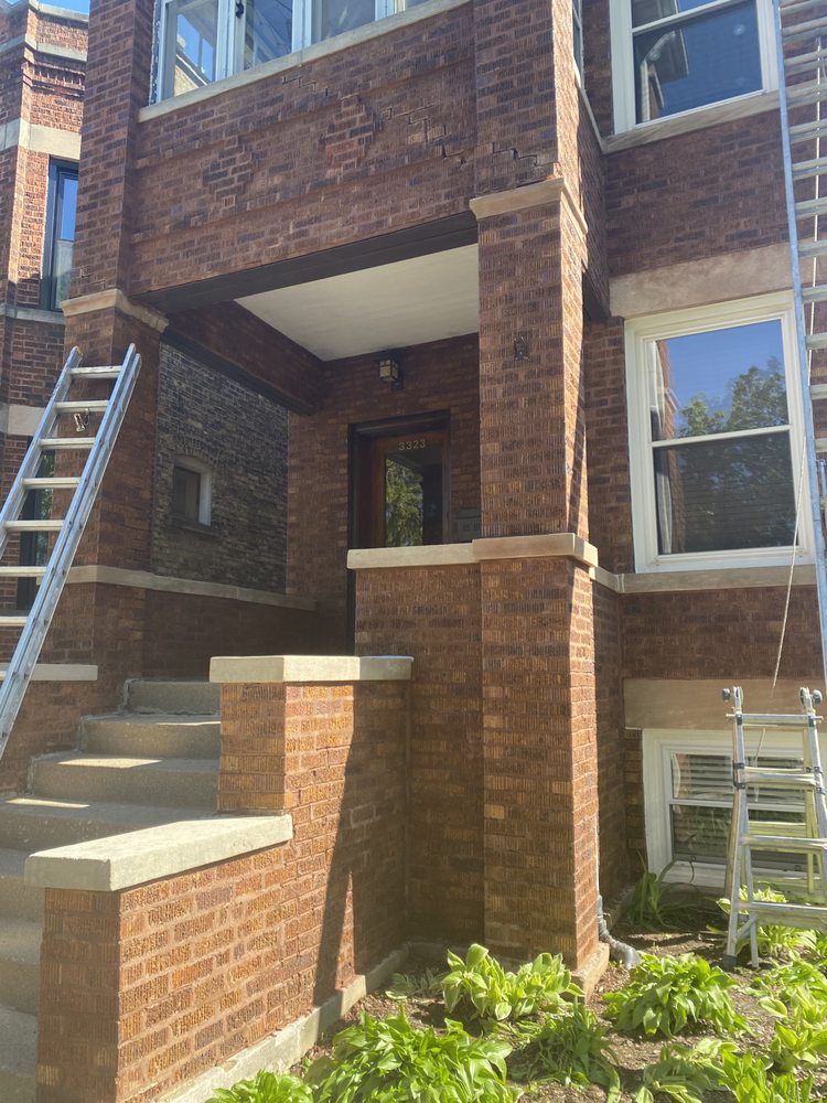 A brick building with stairs and a ladder in front of it.