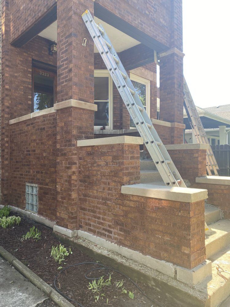 A ladder is hanging from the side of a brick building.