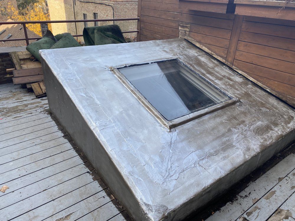 A skylight is sitting on top of a concrete platform on a deck.