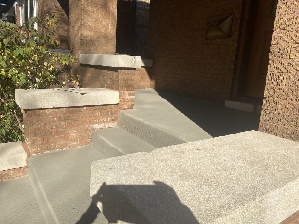 A brick building with a concrete porch and stairs