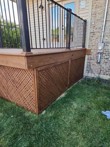 A wooden deck with a metal railing is sitting on top of a lush green lawn.